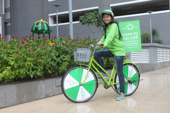 Tình nguyện viên của chương trình trong trang phục và chiếc xe đạp màu xanh lá cây.